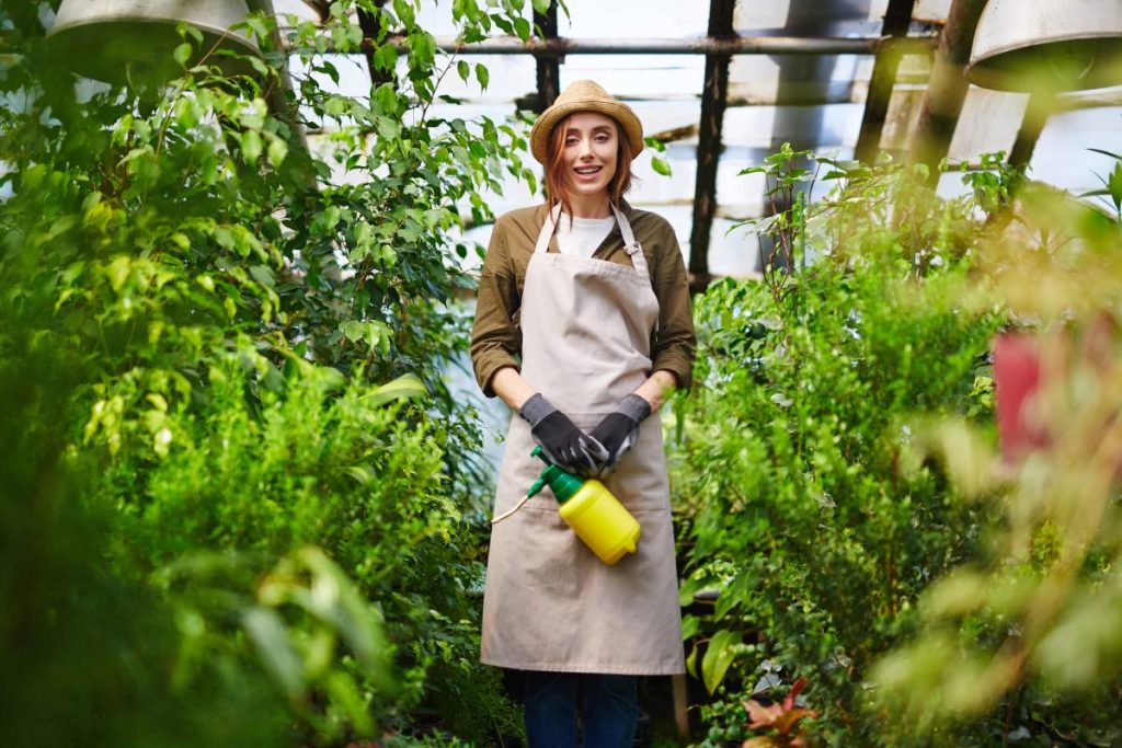 Happy young farmer looking at camera in greenhouse